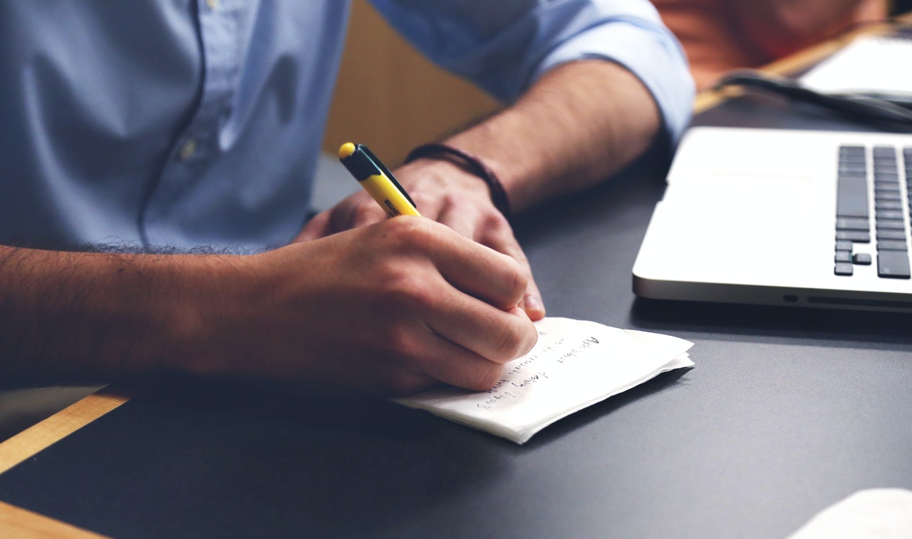 a person writes on a paper using a yellow pen